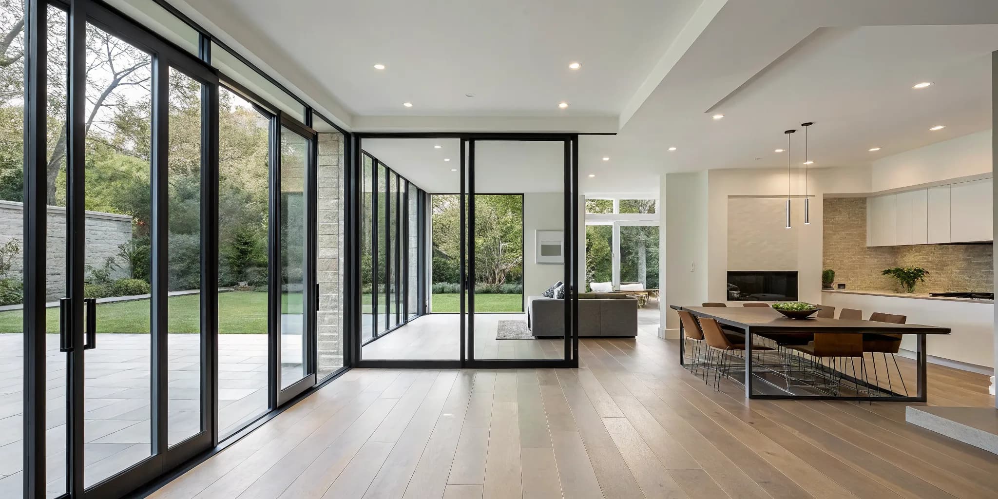 Modern living room with large glass bifold doors opened wide to a garden patio.